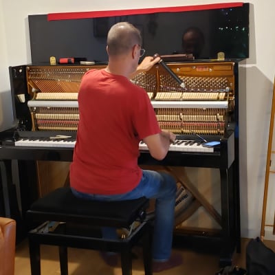 אדם מכוון פסנתר עם כלי כיוון ביד