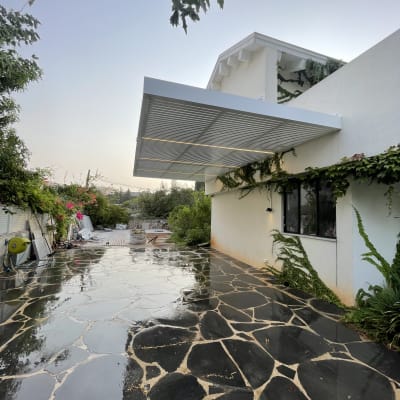 פרגולה אלומיניום בחצר עם רצפת אבן רטובה