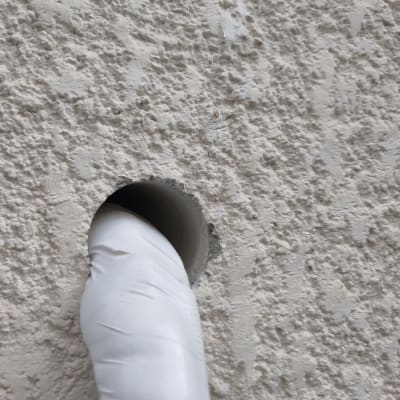 צינור לבן עובר דרך קיר מחוספס
