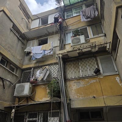 אדם עובד בגובה על בניין עם חבלים וכלים