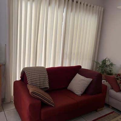 וילון לבן תלוי על מוט מעל ספה אדומה