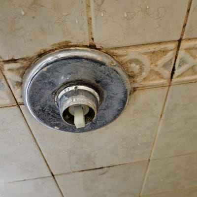 ברז מים ישן עם חלודה על אריחים