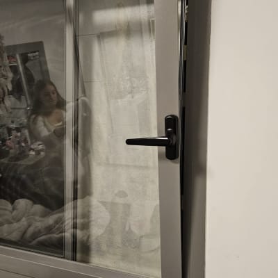 חלון פתוח עם תריסים אפורים וידית שחורה