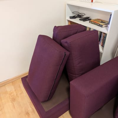 כריות ספה סגולות מונחות על רצפה ליד מדף ספרים