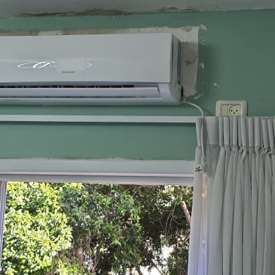 מזגן מותקן על קיר ירוק עם וילון לבן