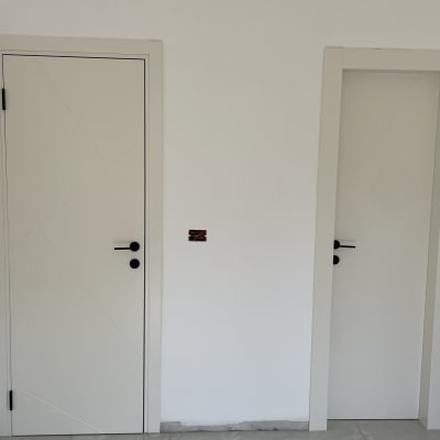 שתי דלתות לבנות עם ידיות שחורות על קיר לבן