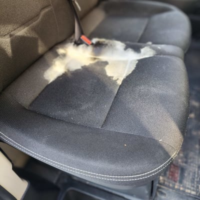 כתם על מושב רכב כהה לפני ניקוי