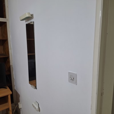 קיר צבוע עם מראה ומתג חשמל