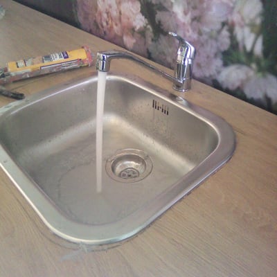 ברז מים זורם בכיור נירוסטה עם כלים