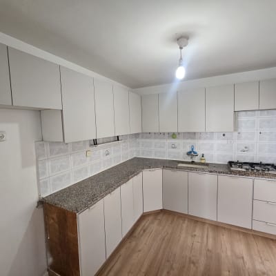 מטבח חדש עם ארונות לבנים ומשטח עבודה מעץ