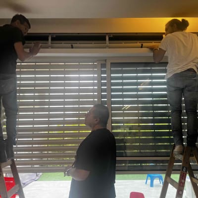 שני אנשים מתקנים תריסים על סולמות