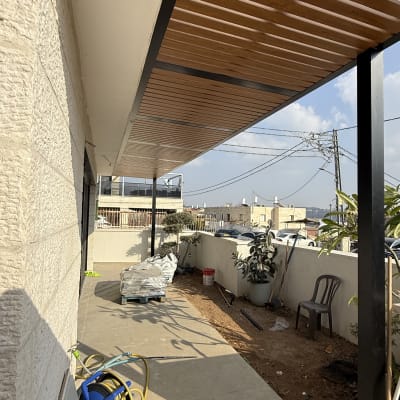 פרגולה מעץ ומתכת בחצר עם ציוד בנייה