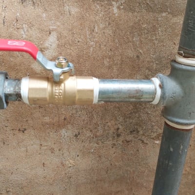 שסתום פליז עם ידית אדומה על צינור מתכת