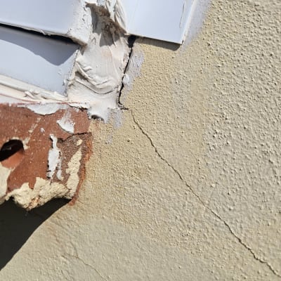 סדק בקיר ליד חלון עם טיח מתקלף