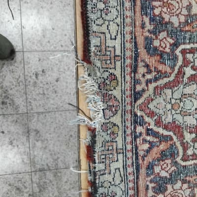 שטיח עם קצה פרום על רצפה אפורה