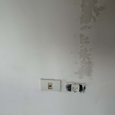 קיר עם תיקוני צבע ושקע חשמל