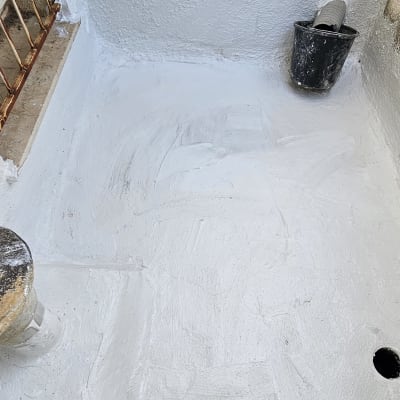 קיר ורצפה אטומים בצבע לבן עם דלי שחור