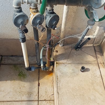 צינור ירוק מחובר לברזים ומד מים על קיר