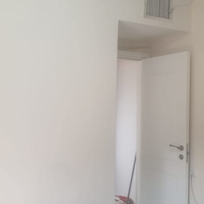 קיר צבוע בלבן עם דלי צבע ומברשת