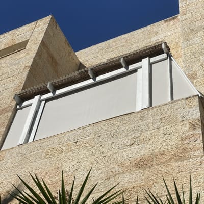 סוכך לבן מותקן על קיר אבן חיצוני