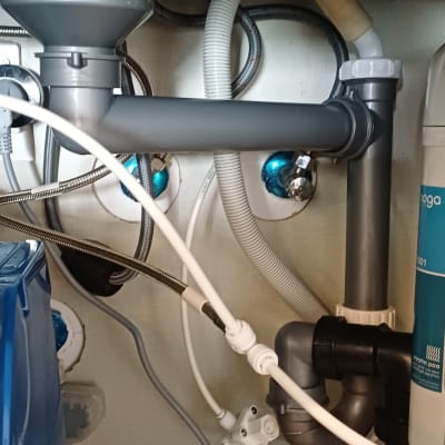 צנרת מתחת לכיור עם חיבורים וצינורות פלסטיק