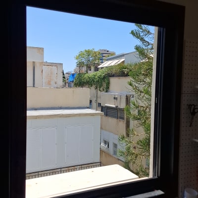 חלון פתוח עם נוף של בניינים ועצים בחוץ