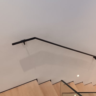 מעקה מתכת שחור ומסגרת זכוכית במדרגות עץ