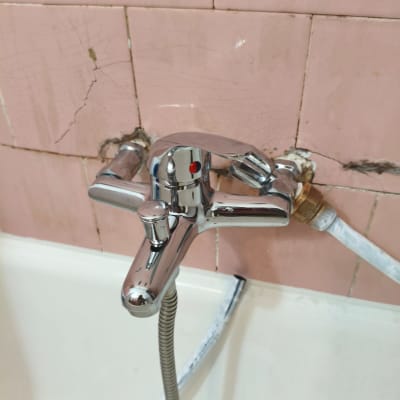 ברז אמבטיה מותקן על קיר עם אריחים סדוקים