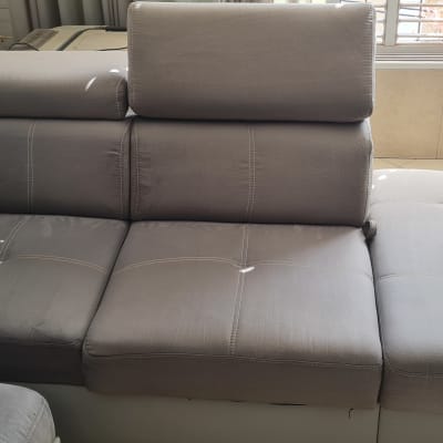 ספת בד פינתית בגוון אפור לצד בקבוק התזה לניקוי ריפודים