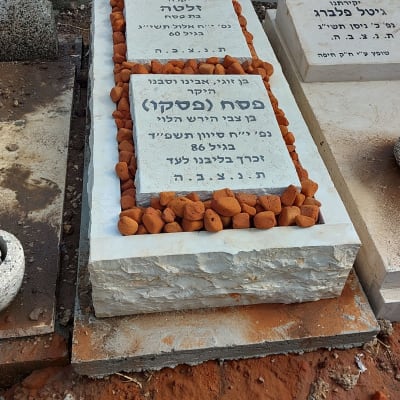 מצבות עם כיתוב בעברית ואבנים קטנות מסביב