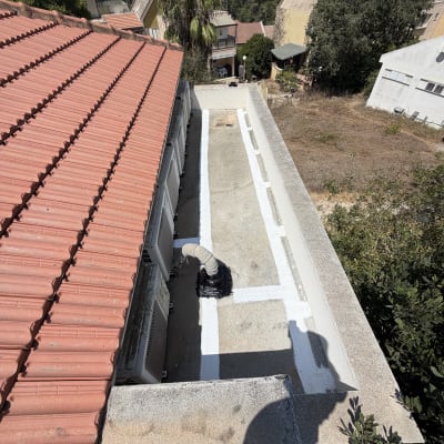 גג עם איטום לבן ליד גג רעפים אדום
