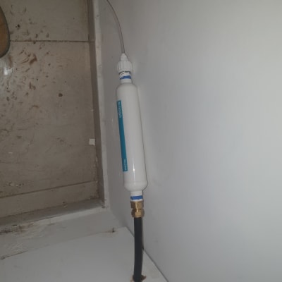 מסנן מים מותקן על קיר עם צינור מחובר