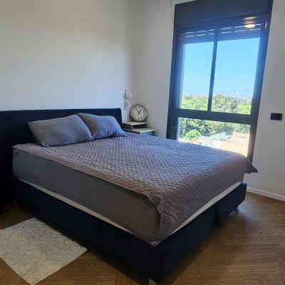 חדר שינה מסודר עם מיטה, מאוורר תקרה ושעון על שידה