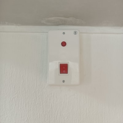 מתג חשמלי עם כפתור אדום על קיר לבן