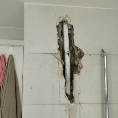 צינור חשוף בקיר שבור בחדר אמבטיה