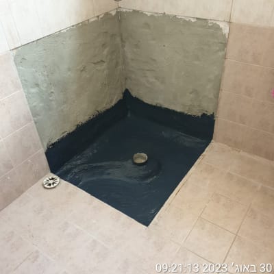 איטום רצפת מקלחת עם חומר שחור סביב הניקוז