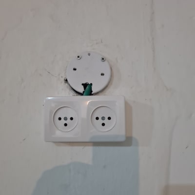 שקע חשמלי כפול על קיר עם חוט חשמל חשוף