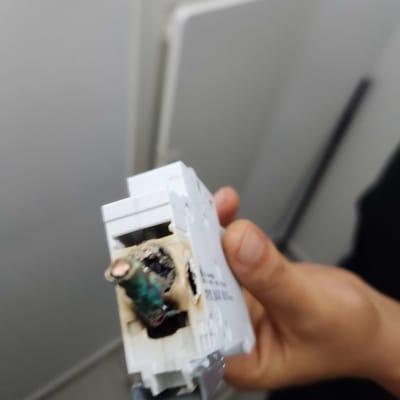 חלק חשמלי עם חוטים שרופים מוחזק ביד