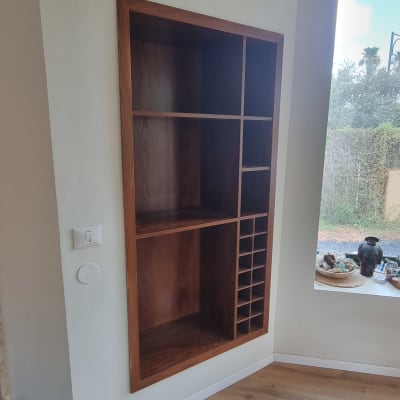ארון עץ מובנה בקיר עם מדפים ותאים