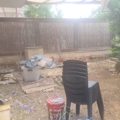 חצר עם עציצים, כיסאות פלסטיק ודלי אדום