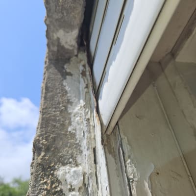 תריס מתכת ישן עם חלודה וקיר בטון מתקלף