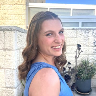 אישה עם שיער גלי ואיפור עדין מחייכת