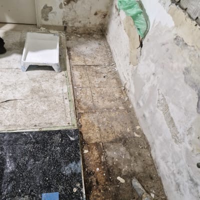 קיר מתקלף עם צינור חשוף, מגש צבע על הרצפה