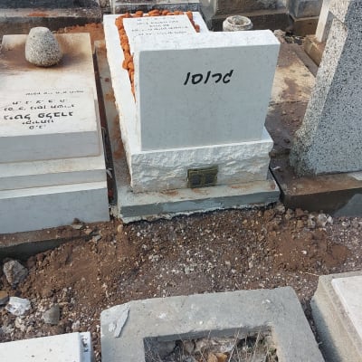 מצבות בבית קברות עם כתובות בעברית ואבנים קטנות