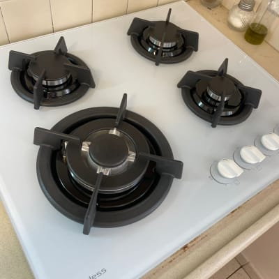 כיריים גז לבנים עם ארבעה מבערים וכפתורי שליטה