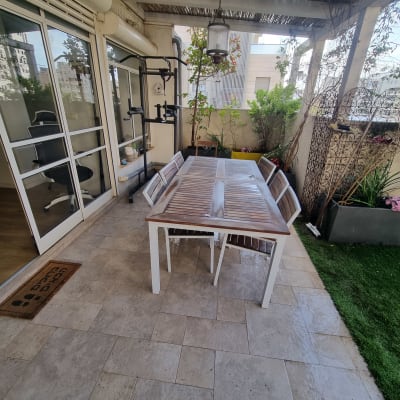 פינת ישיבה עם שולחן וכיסאות במרפסת עם צמחים