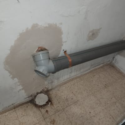 צינור פלסטיק אפור מחובר לקיר עם חיבור T