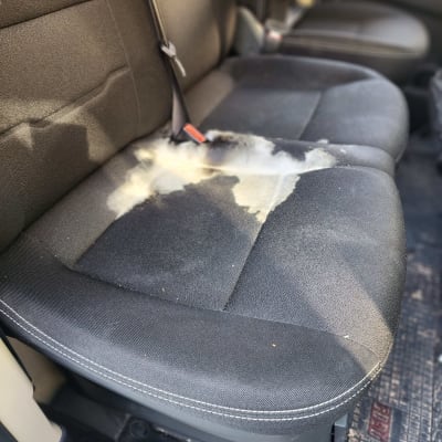 כתם על מושב רכב כהה לפני ניקוי