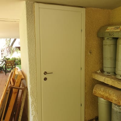 דלת לבנה עם ידית מתכת, מותקנת בקיר חיצוני