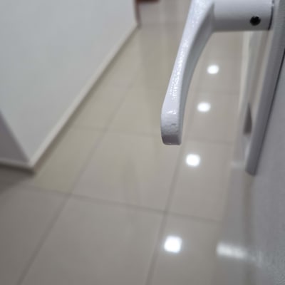 ידית דלת לבנה במסדרון עם רצפת אריחים